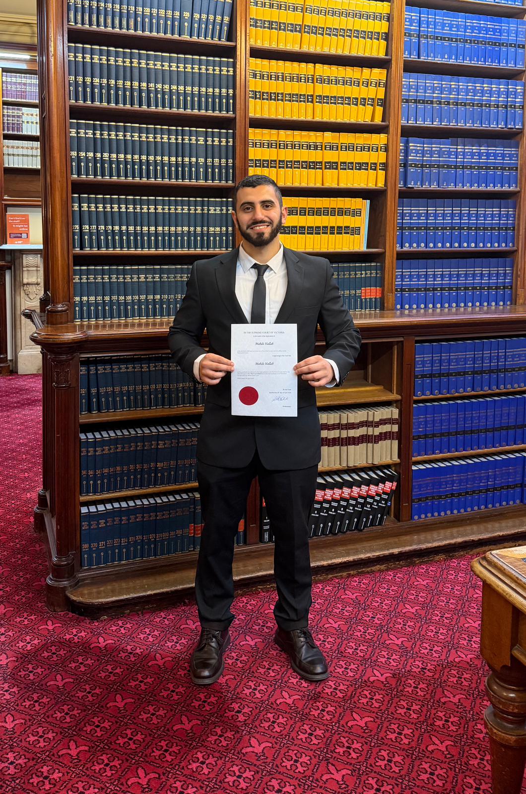 Mahde Hallab holding his Supreme Court of Victoria admission certificate